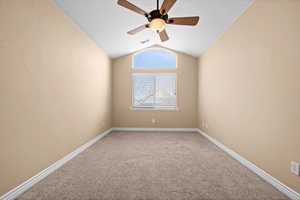 Carpeted spare room with lofted ceiling and ceiling fan