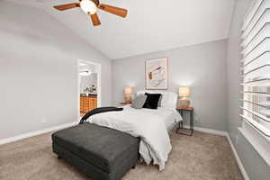 Carpeted bedroom featuring vaulted ceiling, ceiling fan, and ensuite bath