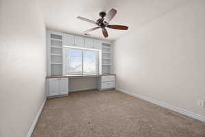 Bedroom or office featuring light carpet, built in shelves, and ceiling fan