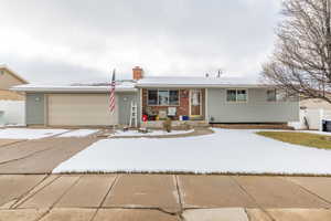 Single story home featuring a garage, covered porch, driveway, and a chimney