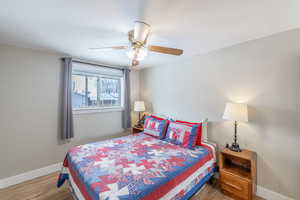 Bedroom with ceiling fan, wood finished floors, and baseboards