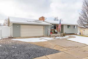 Ranch-style home with a garage, fence, and a chimney