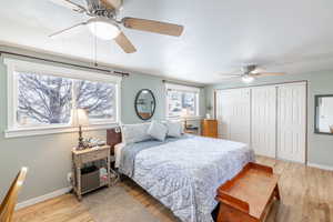 Bedroom featuring a closet, light wood-style flooring, a ceiling fan, a textured ceiling, and baseboards