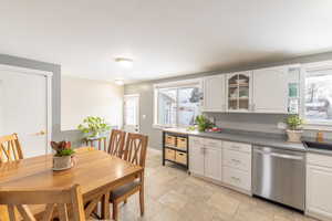 Kitchen featuring dishwasher, a wealth of natural light, glass insert cabinets, and white cabinets