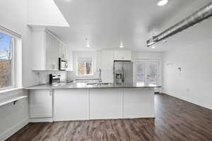 Kitchen with appliances with stainless steel finishes, white cabinets, sink, and kitchen peninsula