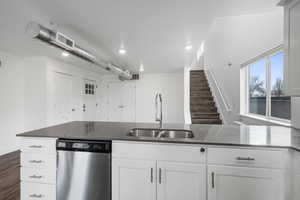 Kitchen featuring white cabinets, dark stone countertops, sink, and stainless steel dishwasher