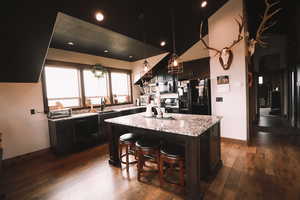 Kitchen with light granite counters, a kitchen island, black appliances, a kitchen bar, and pendant lighting.