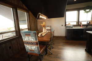 Dining area featuring dark wood-type flooring, wood walls, and baseboards