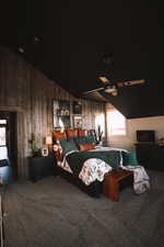 Carpeted primary bedroom featuring lofted ceiling, wood walls, and ceiling fan