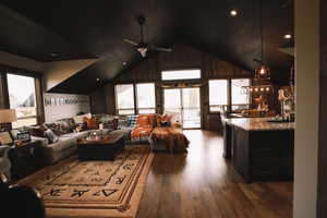 Living area with vaulted ceiling, dark wood-style flooring, plenty of natural light, and a ceiling fan.