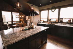 Kitchen with light stone counters, pendant lighting, and a kitchen island