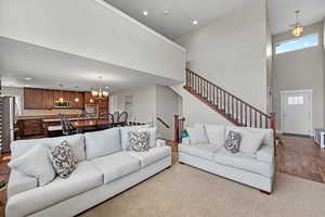Living room featuring light wood-type flooring, a high ceiling, and a chandelier