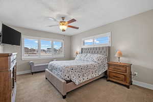 Carpeted bedroom featuring ceiling fan and a textured ceiling