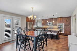 Dining area with dark hardwood / wood-style flooring, a textured ceiling, french doors, and a notable chandelier