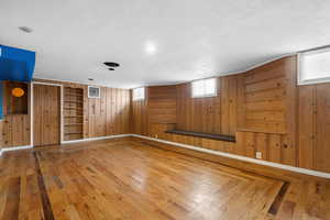 Interior space featuring hardwood / wood-style floors, wooden walls, and a textured ceiling