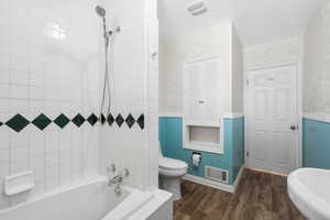 Bathroom with toilet, hardwood / wood-style flooring, and tiled shower / bath combo