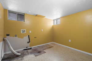 Laundry room featuring hookup for an electric dryer, a textured ceiling, and hookup for a washing machine