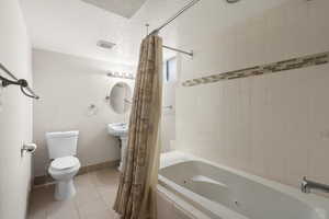 Bathroom featuring shower / tub combo with curtain, tile patterned flooring, toilet, and a textured ceiling