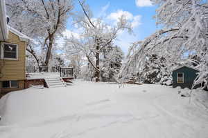 Yard layered in snow featuring a wooden deck