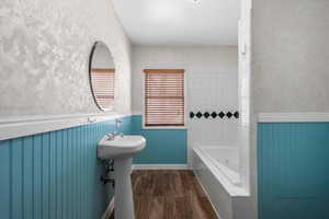 Bathroom with tiled bath, hardwood / wood-style flooring, and sink