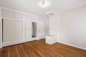 Unfurnished bedroom with dark wood-type flooring