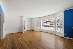 Unfurnished living room featuring hardwood / wood-style flooring, plenty of natural light, and a textured ceiling