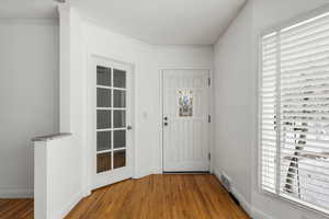 Foyer entrance with hardwood / wood-style floors and crown molding