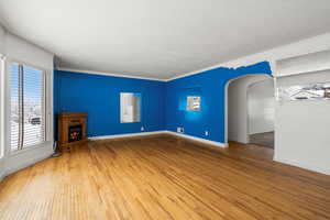 Unfurnished living room featuring hardwood / wood-style flooring and ornamental molding