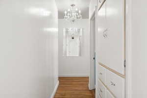 Corridor featuring a notable chandelier and wood-type flooring