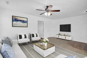 Carpeted living room with visible vents, ceiling fan, and baseboards