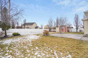 Yard covered in snow featuring a fenced backyard, a shed, a patio, and an outbuilding