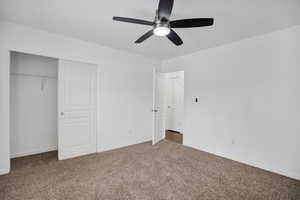 Unfurnished bedroom with carpet, baseboards, ceiling fan, and a closet