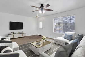 Living room featuring a ceiling fan, visible vents, baseboards, and wood finished floors