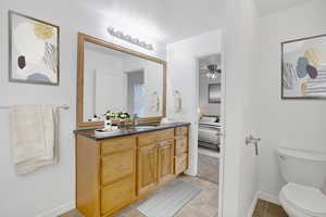 Bathroom featuring toilet, a ceiling fan, vanity, tile patterned flooring, and baseboards