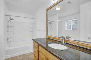 Full bath featuring visible vents, vanity, and tub / shower combination