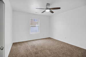 Carpeted empty room featuring ceiling fan, visible vents, and baseboards