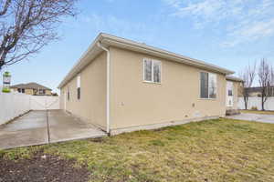 Rear view of property with a patio, a yard, fence, and stucco siding