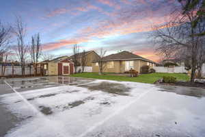 View of front of home featuring a lawn, an outbuilding, fence, a storage unit, and stucco siding