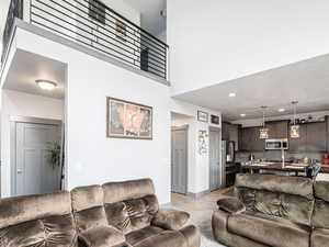 Living area featuring light wood-style floors, recessed lighting, a high ceiling, and stairway