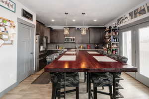 Kitchen featuring stainless steel appliances, dark brown cabinetry, plenty of natural light, and a kitchen island with sink