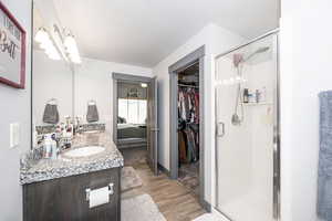 Full bath with a sink, wood finished floors, a shower stall, a textured ceiling, and double vanity