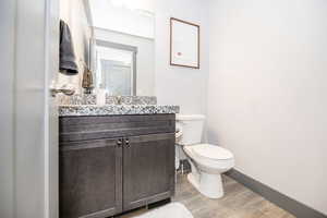 Bathroom with baseboards, vanity, toilet, and wood finished floors