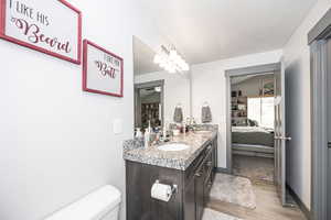 Ensuite bathroom with a sink, wood finished floors, ensuite bathroom, toilet, and double vanity