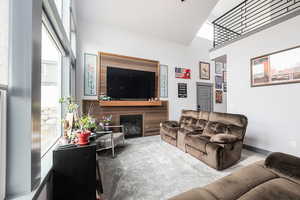 Living room featuring a glass covered fireplace, carpet, and a high ceiling