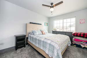 Bedroom featuring a ceiling fan, dark colored carpet, and baseboards