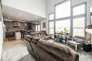 Living room with a towering ceiling, recessed lighting, and light wood-type flooring