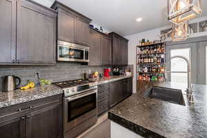 Kitchen featuring a sink, dark brown cabinets, pendant lighting, and stainless steel appliances