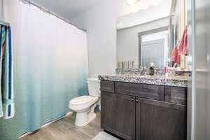 Bathroom featuring vanity, toilet, and wood finished floors