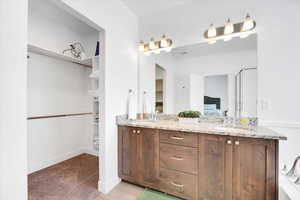 Ensuite bathroom with a walk in closet, double vanity, a sink