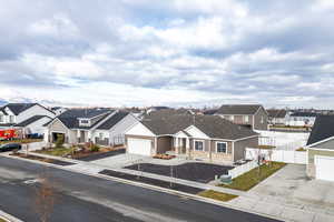 View of front facade featuring a garage, fence, stone siding, driveway, and a residential view